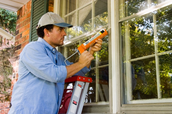 Construction worker caulking window trim