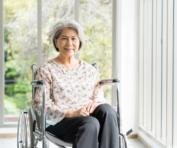 Older woman in wheelchair standing in front of wall of windows