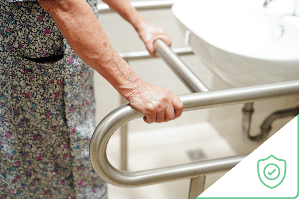 Old woman using grab bar in bathroom